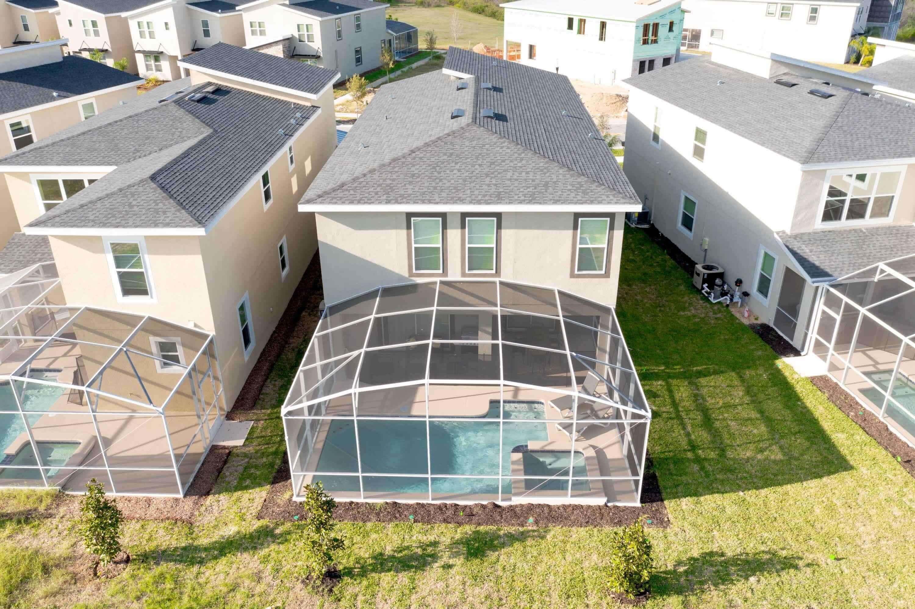 A residential area with multiple houses, a large covered swimming pool, and a well-maintained lawn.