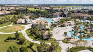Een resort met diverse zwembaden, palmbomen en een golfbaan op de achtergrond.