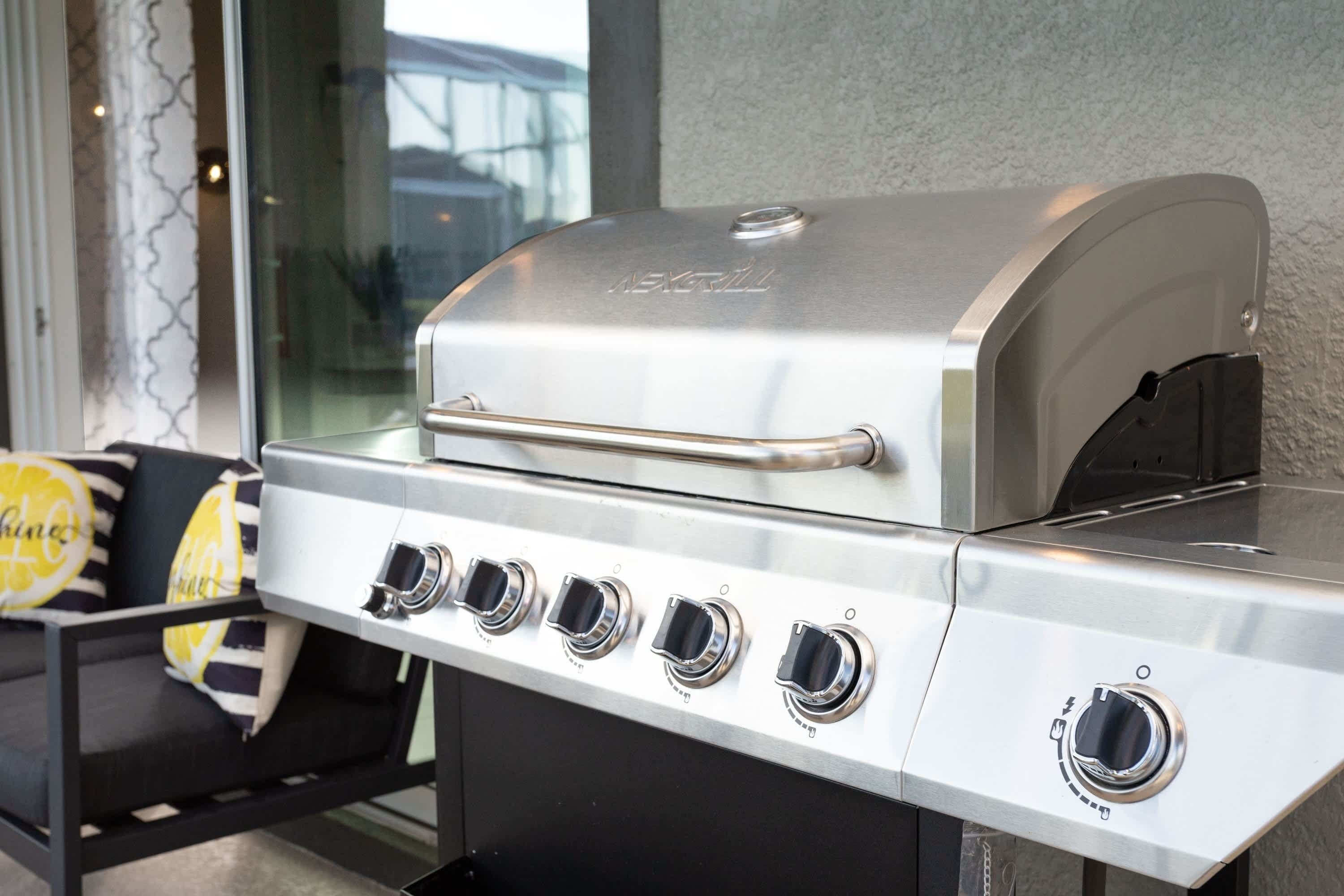 Un barbecue en acier inoxydable doté de quatre brûleurs et d’une ouverture de ventilation sur le côté.