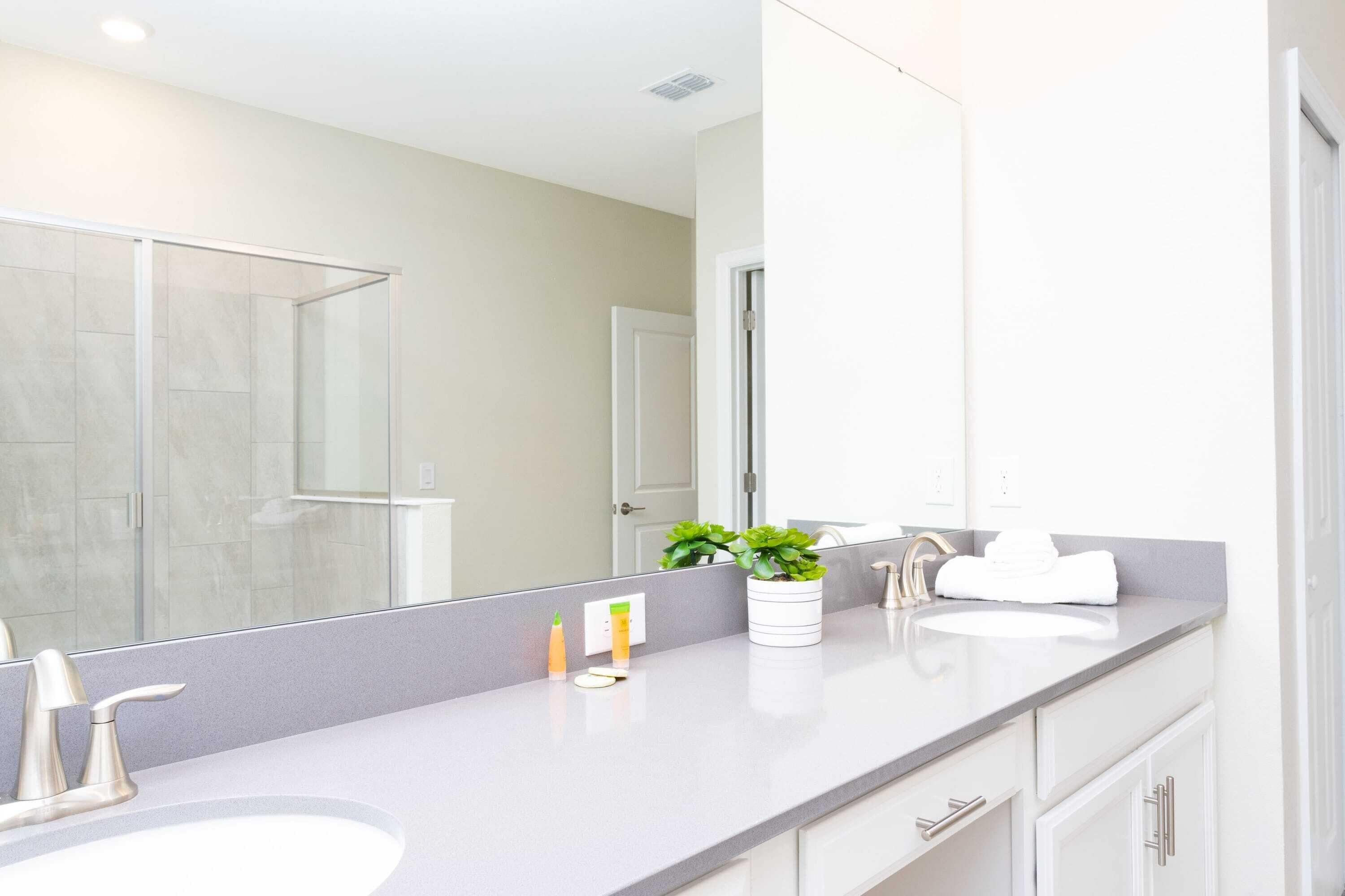 Un baño moderno con dos lavamanos, un espejo grande y una zona de ducha.