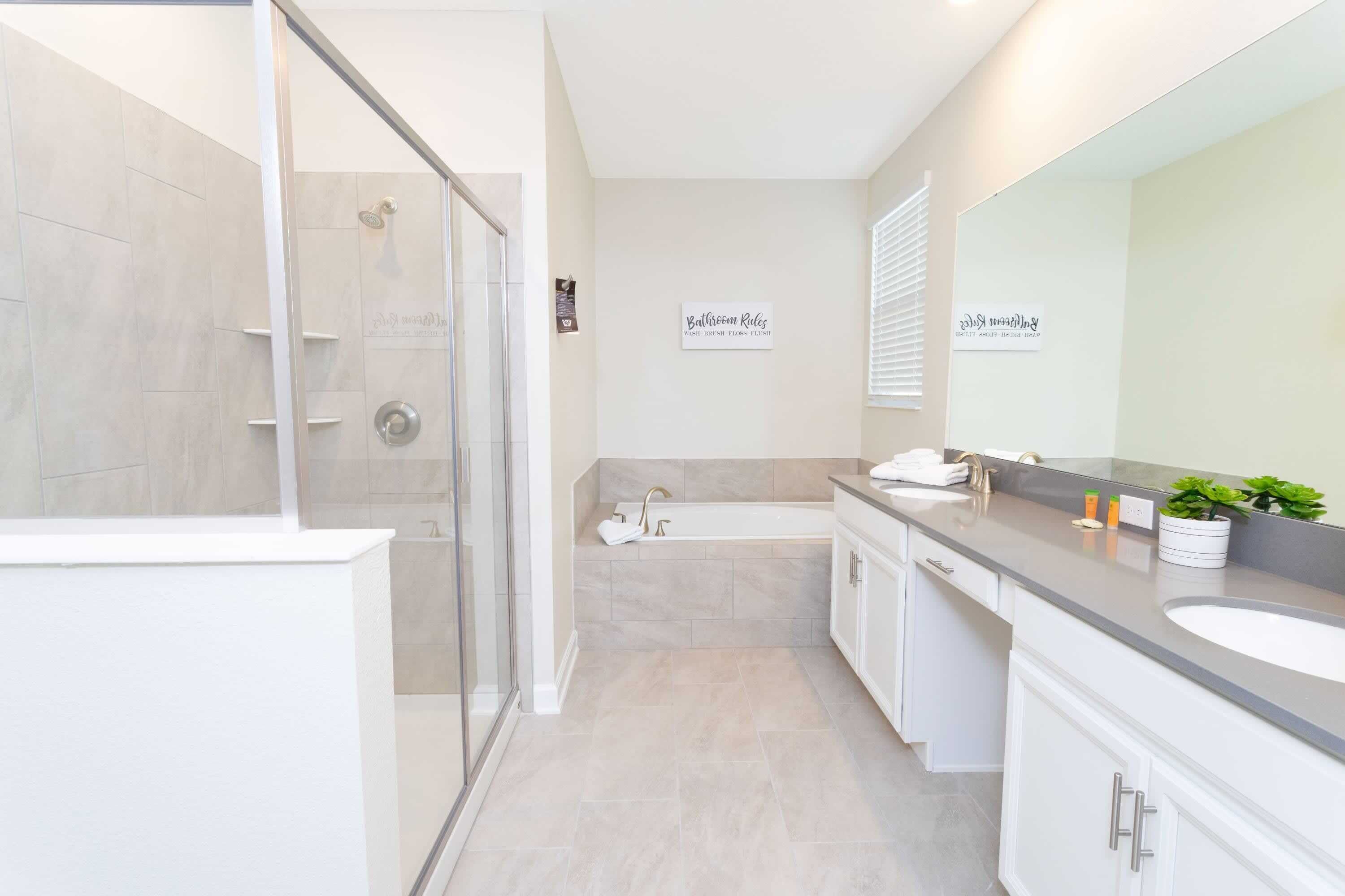 Un baño moderno con cabina de ducha de vidrio, una bañera y un lavamanos con un espejo grande.