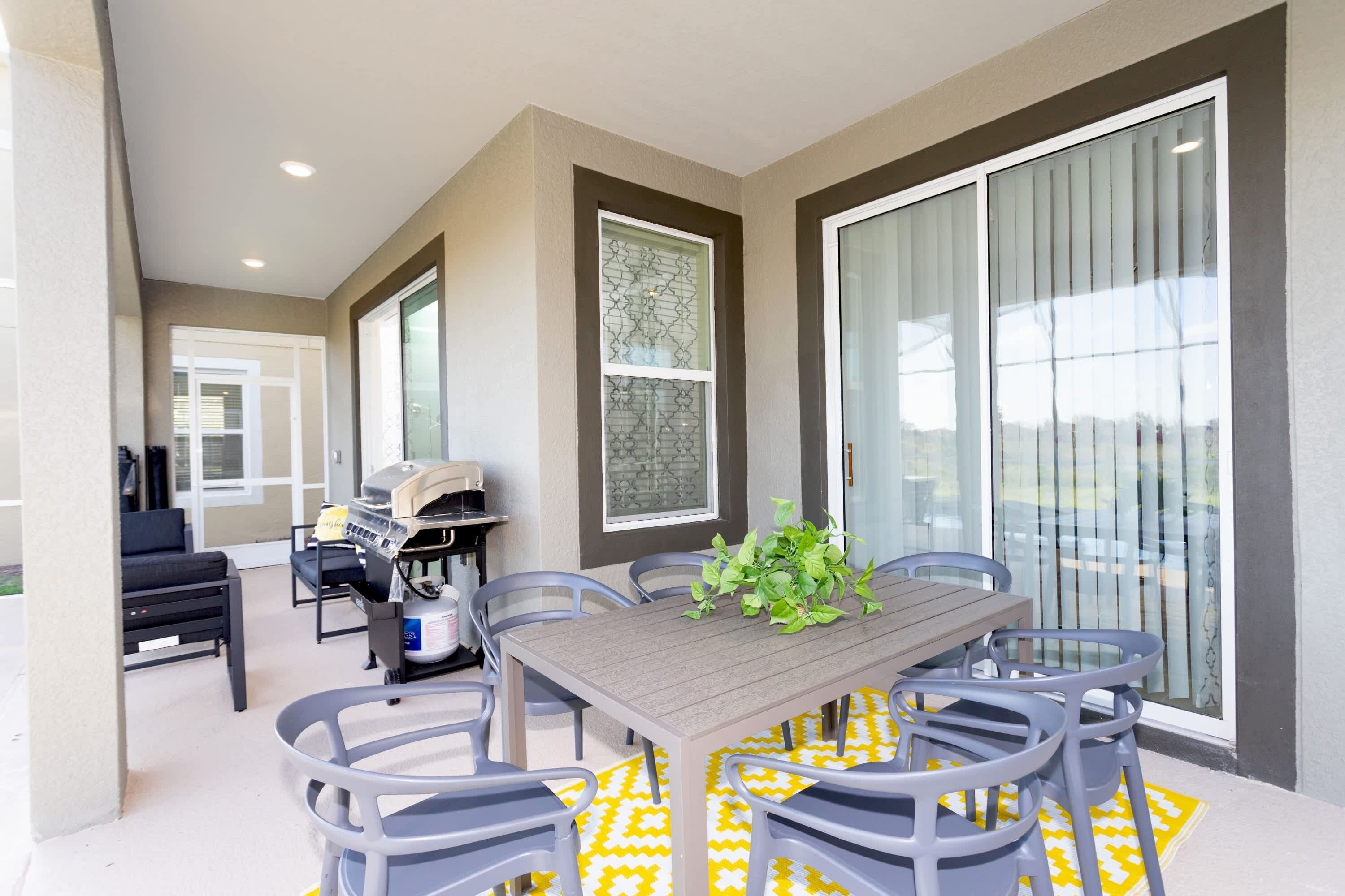A dining area with a table and chairs, a grill, and a sliding glass door.