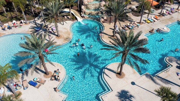A large outdoor swimming pool with palm trees, lounge chairs, and a water slide. - Stunning 5Bd w/ Pool Close to Disney @ Solterra 7829 (Davenport)