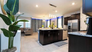 A modern kitchen with dark cabinetry, a stainless steel refrigerator, and a granite countertop. - Stunning 5Bd w/ Pool Close to Disney @ Solterra 7829 (Davenport)