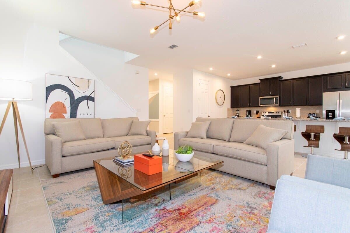 A modern living room with two sofas, a coffee table, and a kitchen in the background.