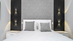 Ein modernes Schlafzimmer mit einem großen Bett, zwei Nachttischen und Wandleuchten.