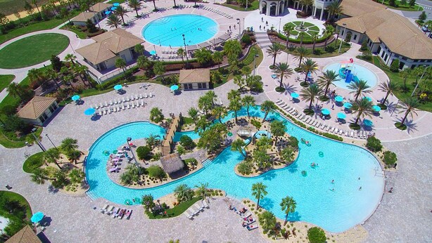Um resort com várias piscinas, espreguiçadeiras e palmeiras.