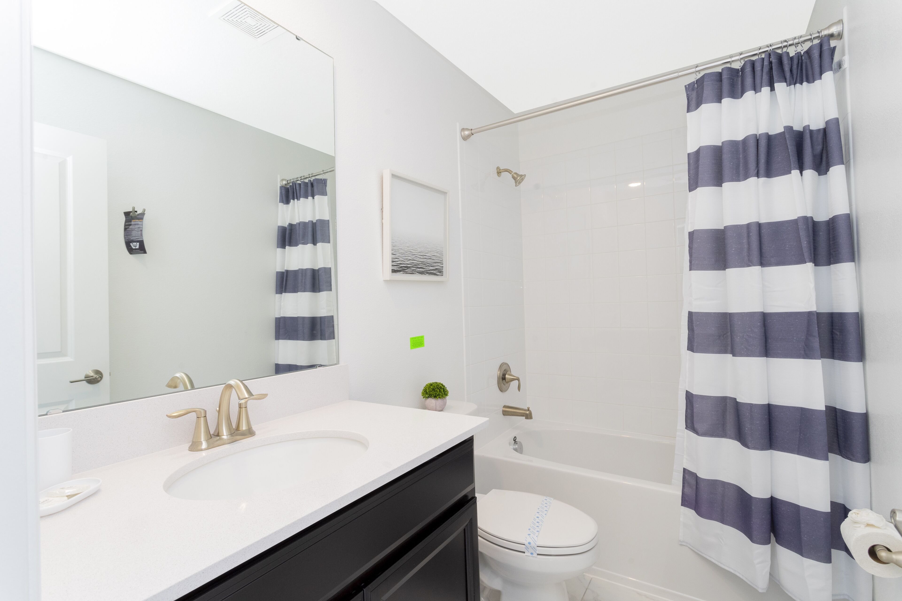 Une salle de bain avec un lavabo blanc, des toilettes, une douche et un rideau à rayures.