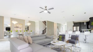 Uma sala de estar moderna com um sofá modular cinza, uma mesa de centro redonda e um lustre.