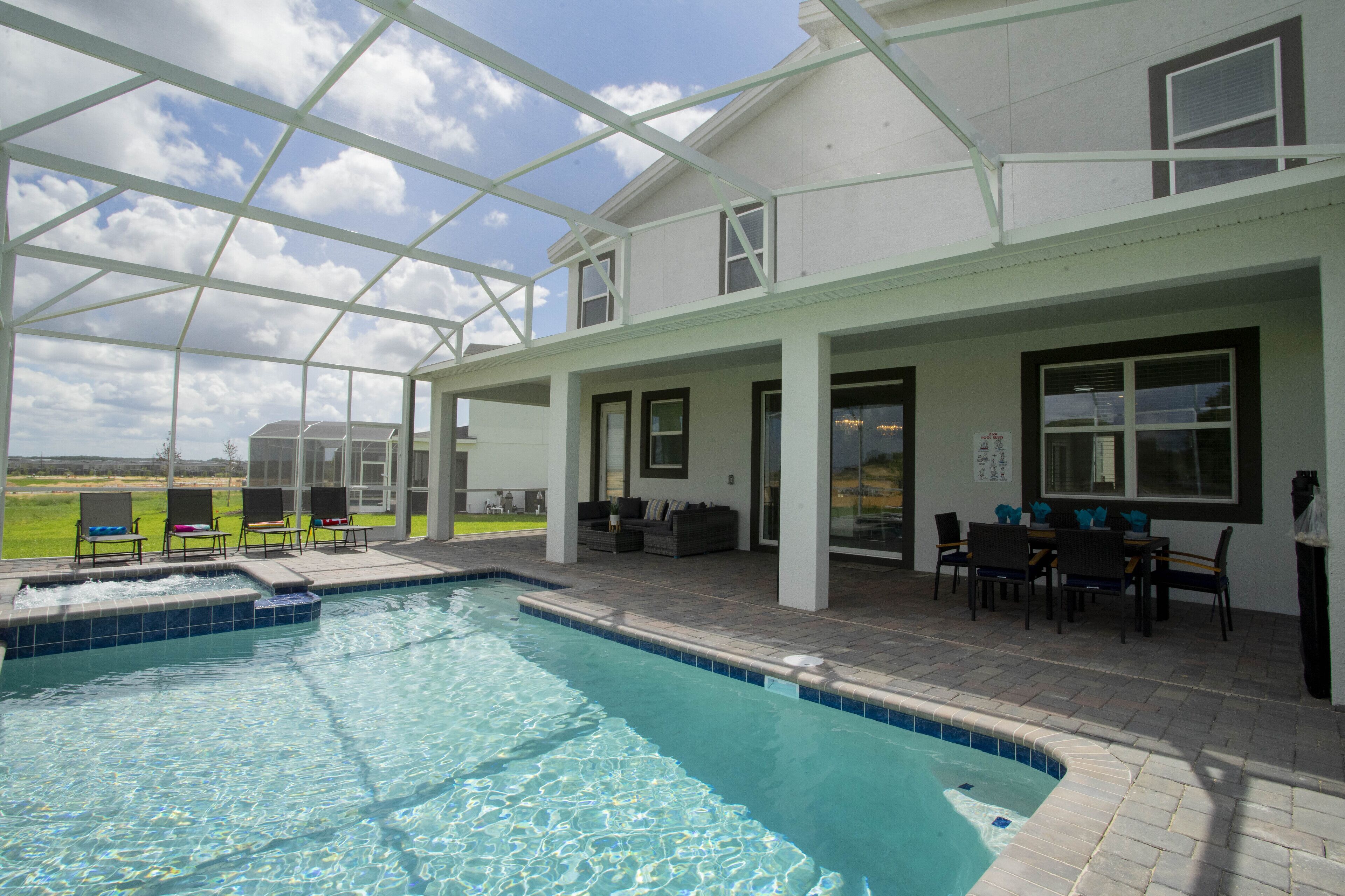 Una piscina con techo de vidrio, mobiliario exterior y vistas al paisaje.