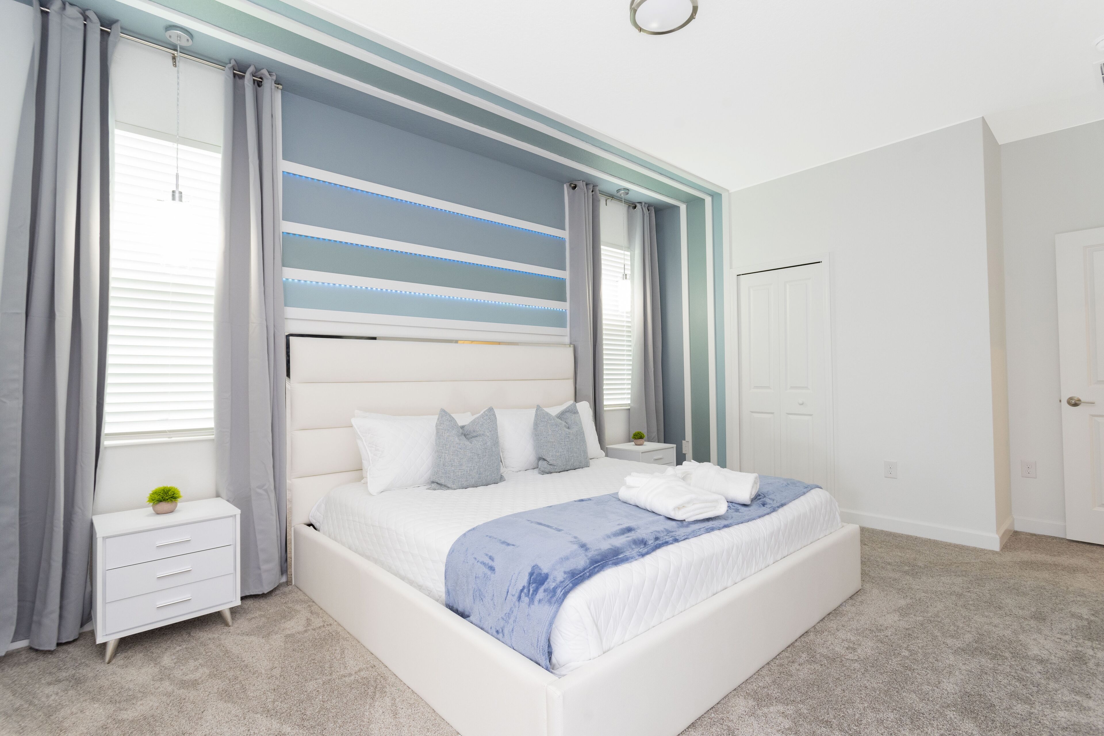 Een moderne slaapkamer met een groot bed, een nachtkastje en een raam met gordijnen.