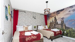Quarto com duas camas, cada uma com colcha temática de Harry Potter, parede de tijolos e um grande mural do castelo de Hogwarts.