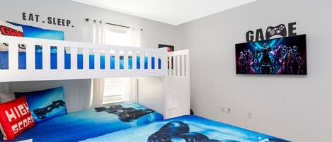 Ein Schlafzimmer mit Etagenbetten, Gaming-Betttwäsche und motivierenden Wandbildern.