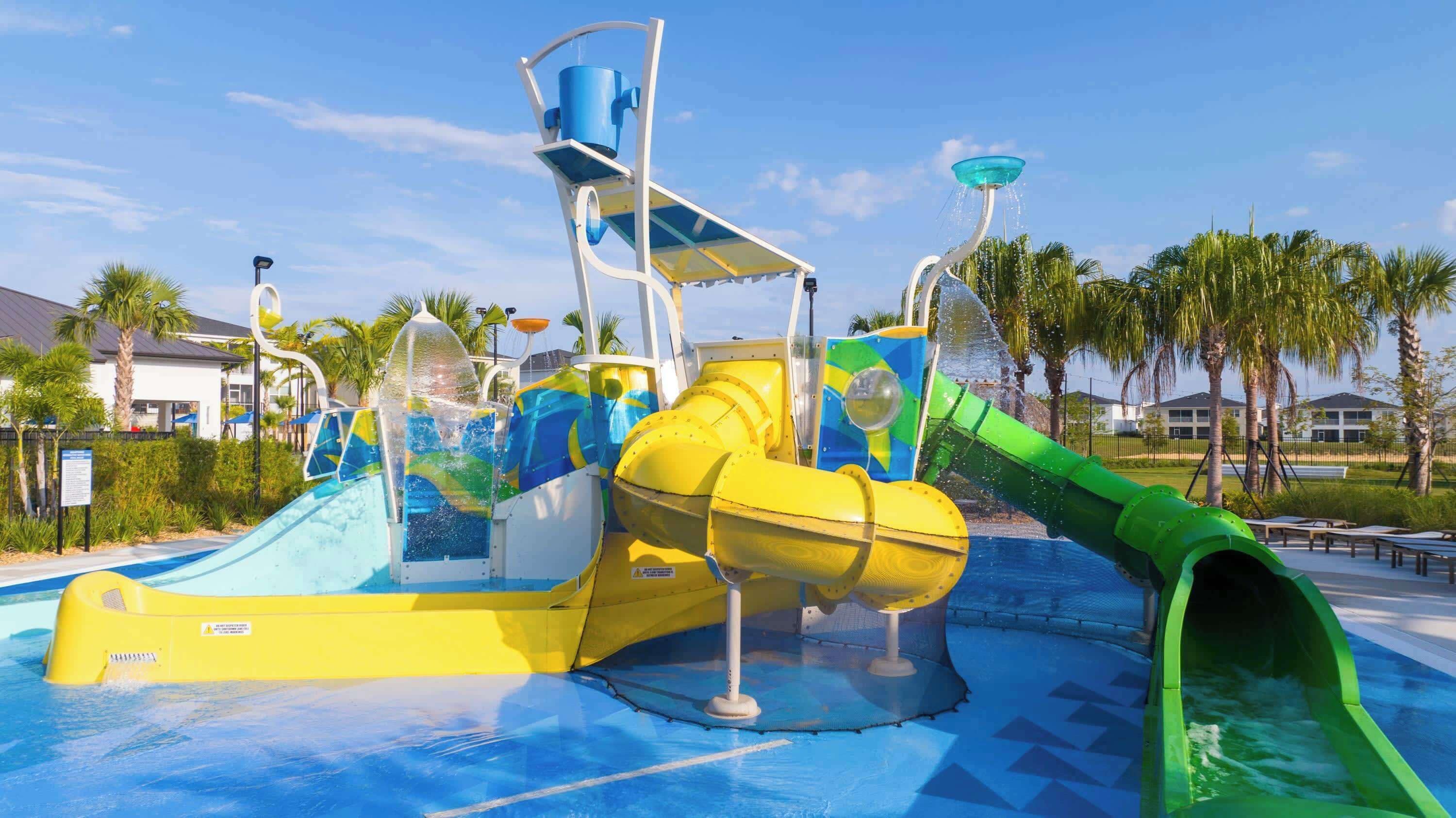 Parque acuático con un tobogán de agua grande, una zona de juegos con agua y una piscina.