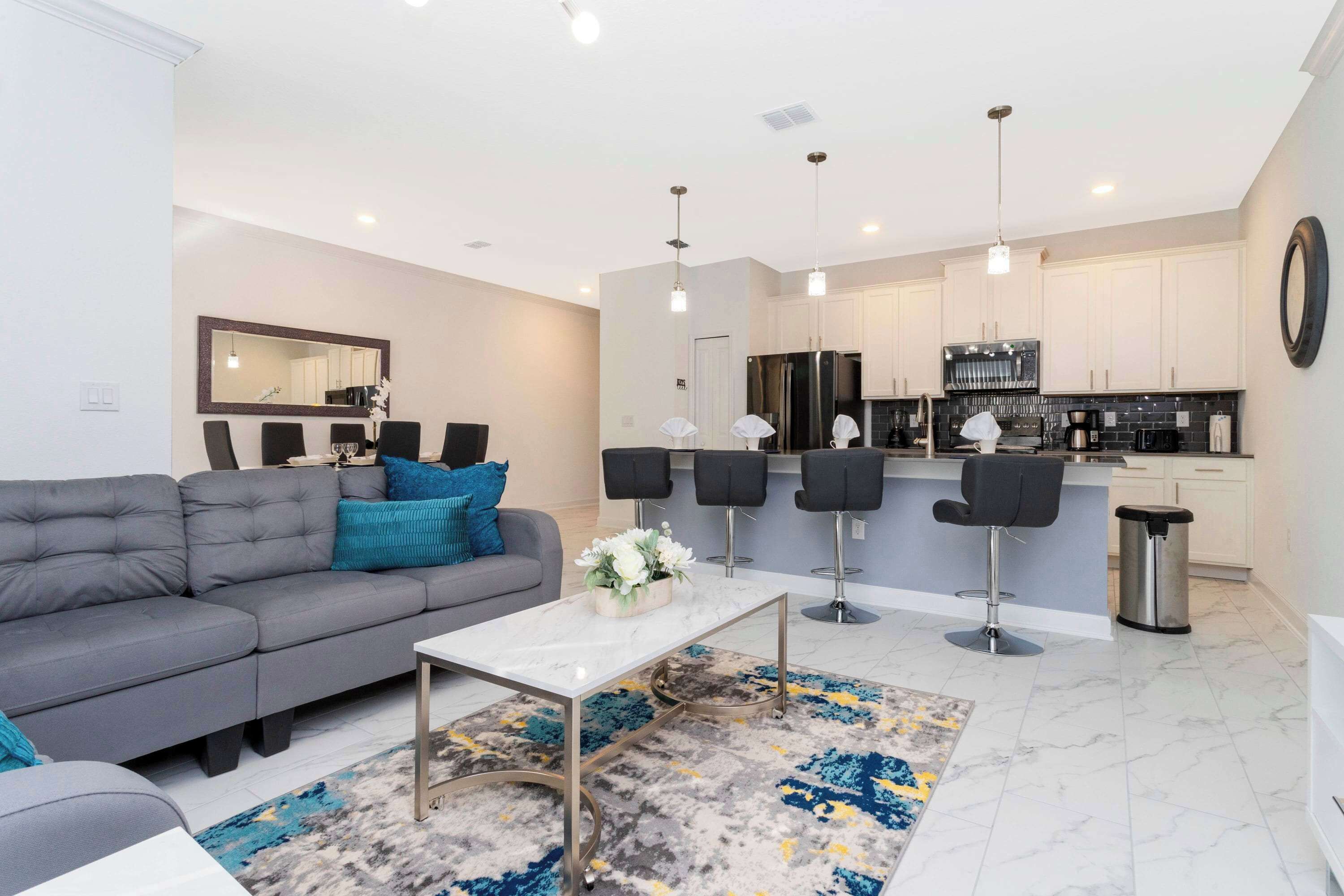 A modern living room with a grey sofa, a white coffee table, and a patterned rug.