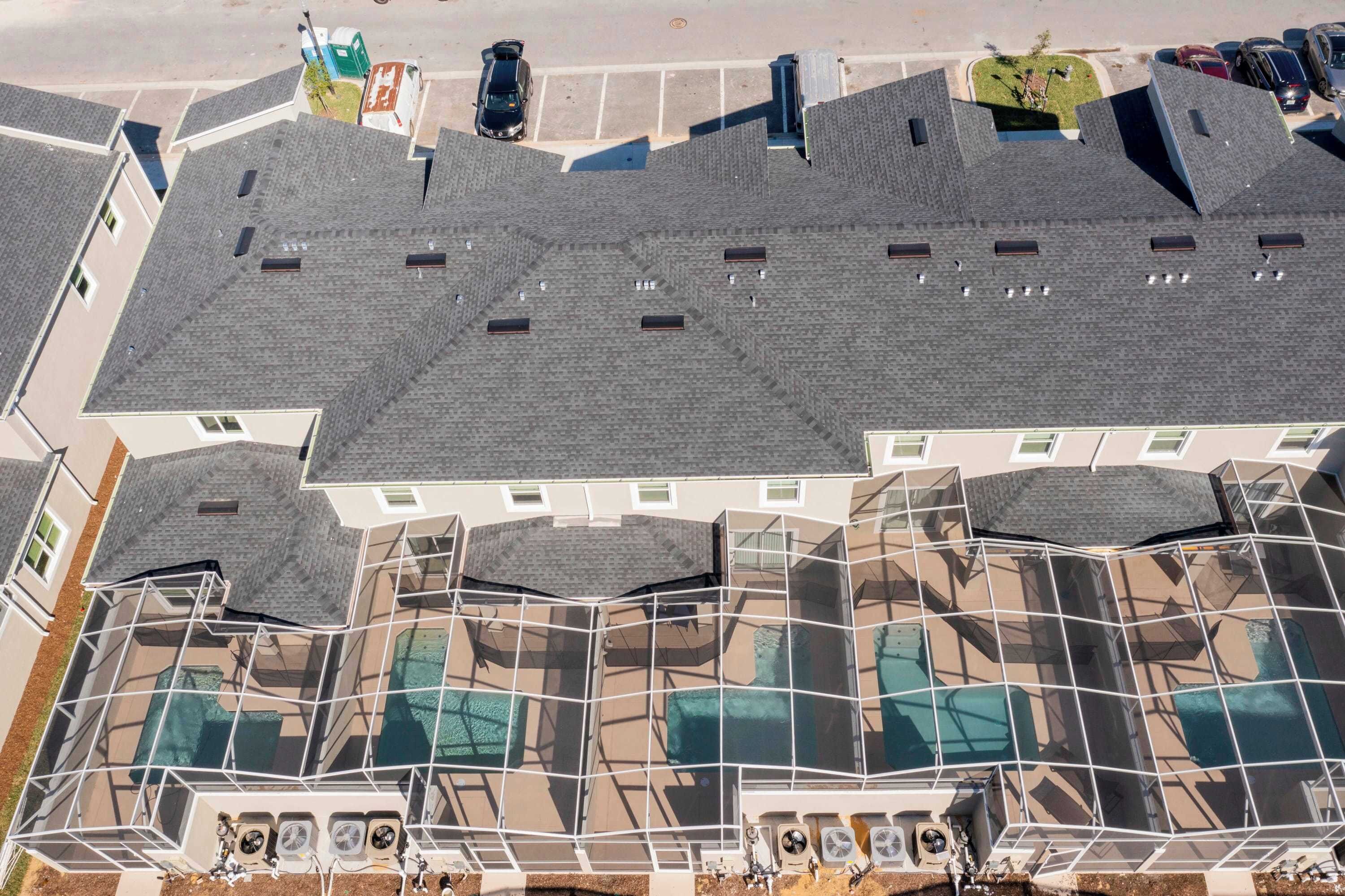 A multi-story building with a distinctive roof design, multiple windows, and a visible pool area.