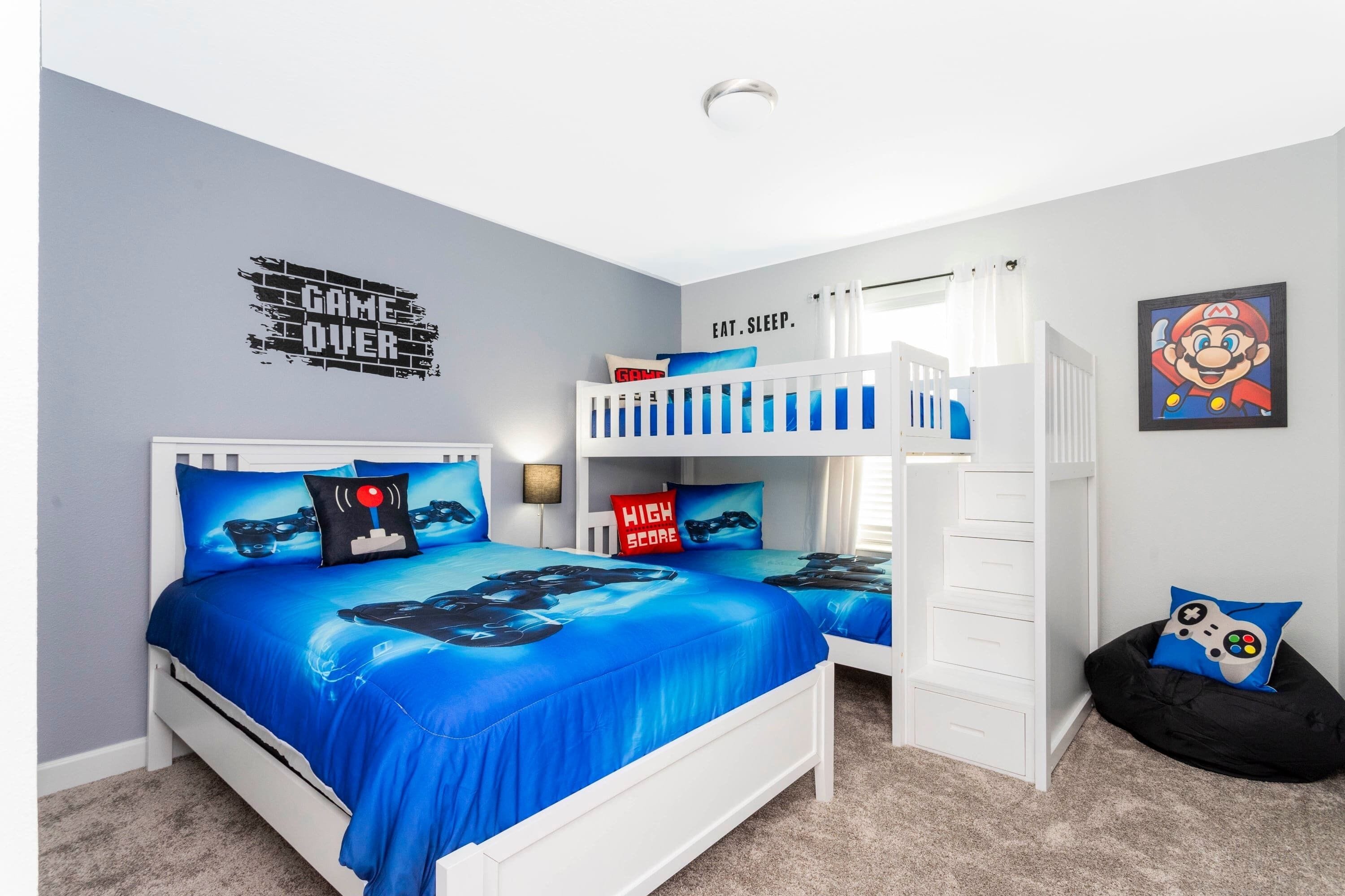A bedroom with a bunk bed, a bed with a blue game-themed bedspread, and a wall with a Mario poster.