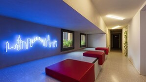 A modern lobby with a neon cityscape sign, red seating, and a plant. - GuestHost - Studio Milan-Corso Magenta! Ac & Wifi! (Milano)