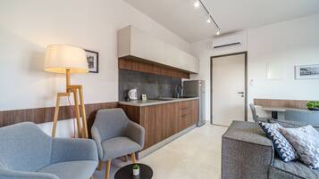 Una sala de estar moderna con sofás grises, una mesita negra y una lámpara de pie de madera.