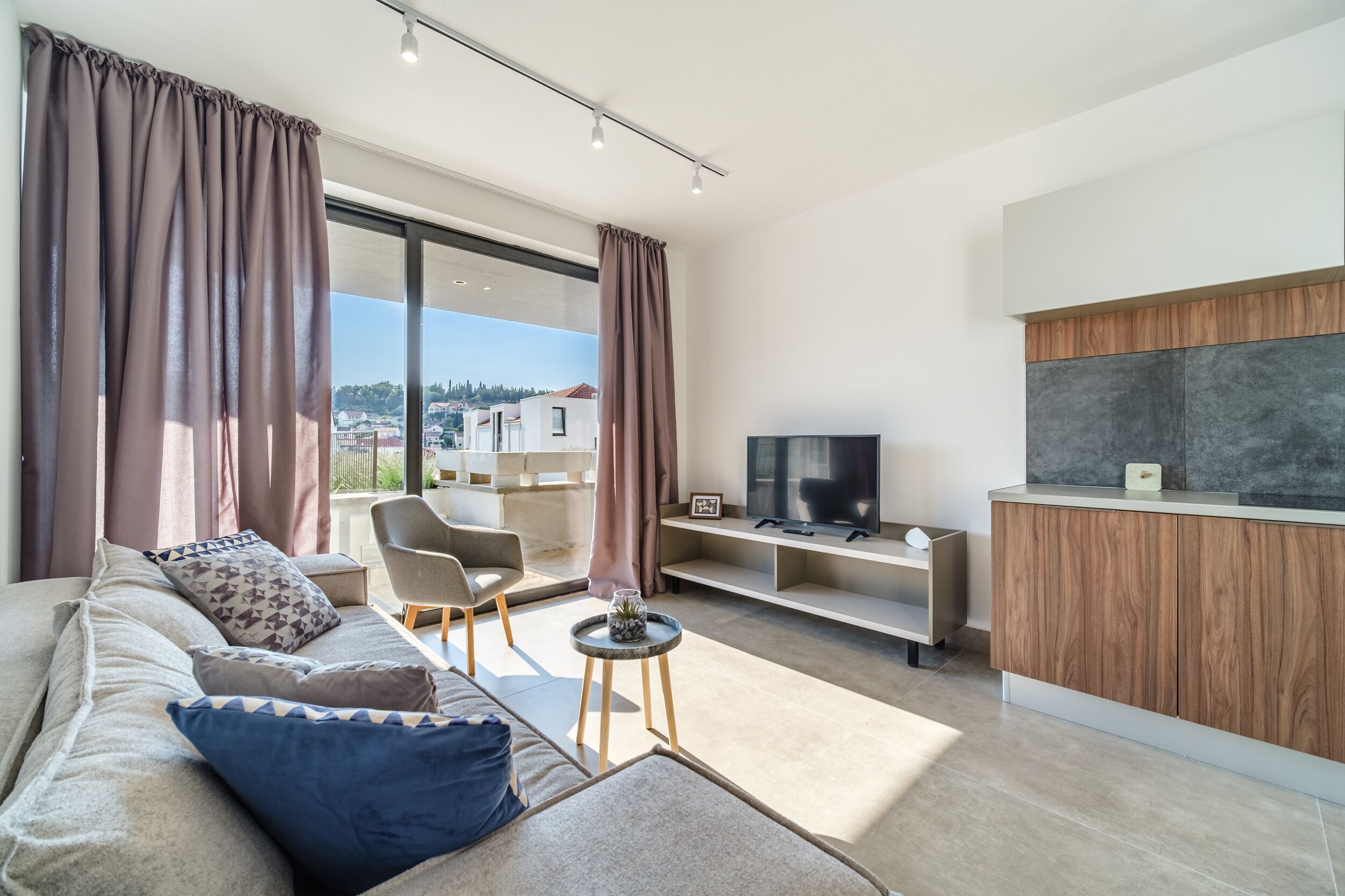 A modern living room with a sofa, TV, and a small table.