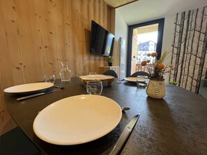 A dining table set with plates, cutlery, and a vase of flowers. - Renovated and comfortable apartment, perfect for family of 4 (Les Gets)