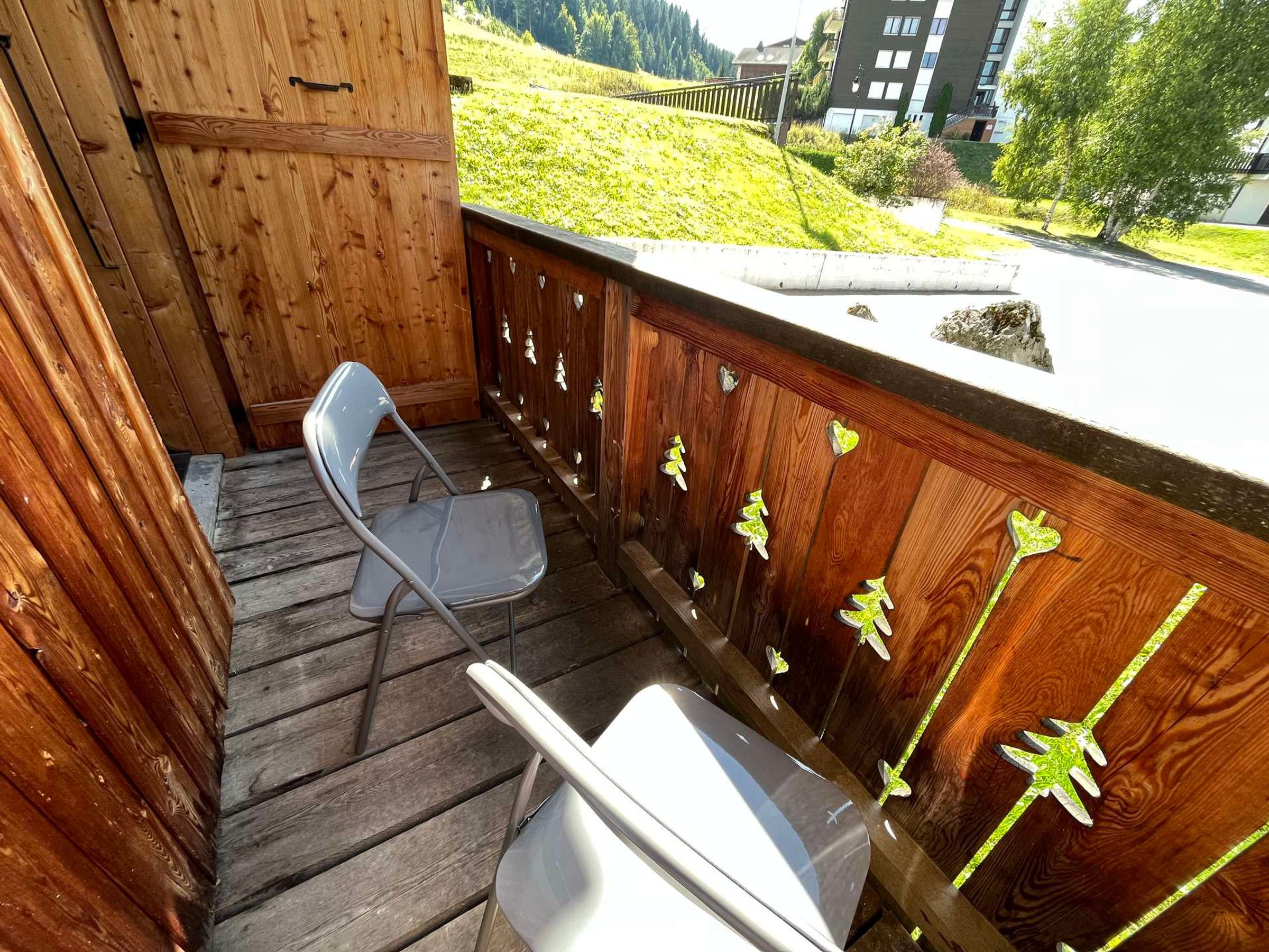 A wooden deck with a metal chair and a white table.