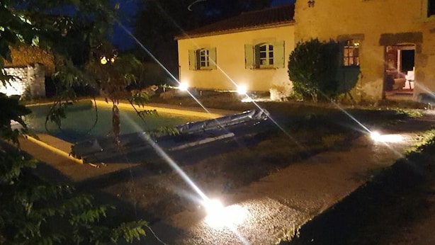 A nighttime view of a house with a swimming pool, illuminated by streetlights.