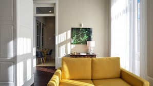 Un sofá amarillo en una habitación bien iluminada, con un comedor al fondo.