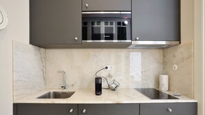 Una cocina moderna con un microondas Bosch, un lavamanos y una encimera con un altavoz y un recipiente de vidrio.