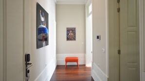 A hallway with wooden flooring, a bench, and two doors. - Superior Studio with Balcony in Bolhão Market (Oporto)