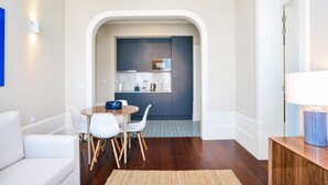 A modern kitchen with dark cabinets, a round dining table, and white chairs. - Exceptional Two-Bedroom, Apart in Bolhão Market (Oporto)