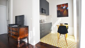 A modern kitchen with dark cabinets, a microwave, and a dining area with a yellow and white patterned floor. - Twin Studio with Balcony in Bolhão Market (Oporto)