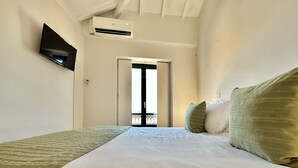 Et hotelværelse med en seng, et fladskærms-tv monteret på væggen og en aircondition-enhed over døren.