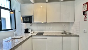 Una cucina moderna con mobili bianchi, un forno a microonde, una macchina da caffè e un lavello.