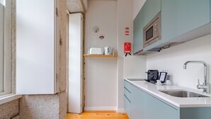 Une cuisine compacte équipée d’un four à micro-ondes, d’une machine à café et d’un évier.