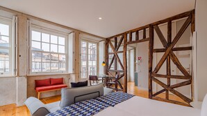 Une chambre avec un grand lit, un banc rouge, une petite table et des poutres en bois.