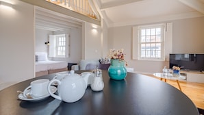 A modern living room with a dining table set for tea, a sofa, and a TV in the background. - Amazing Duplex Two-Bedroom Apart with Views (Oporto)