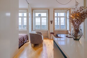 A modern bedroom with a bed, a chair, a small table, and a vase of dried flowers. - Twin Studio in Clérigos Tower (Oporto)
