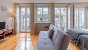 Une chambre moderne avec un canapé, un téléviseur et une petite table.