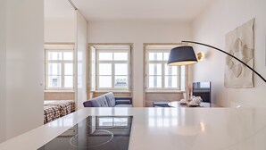 A modern kitchen with a central island, a dining area with a table and chairs, and a sofa in a corner. - Comfy Twin Studio in Clérigos Tower (Oporto)