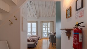 Ein Zimmer mit einem Bett, einem Schreibtisch und einem Feuerlöscher an der Wand.