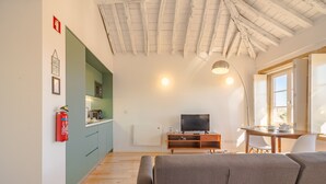 Un salon moderne comprenant un canapé, un téléviseur et un coin repas avec une table et des chaises.