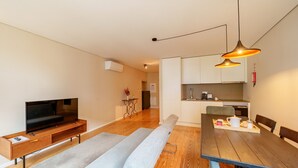 Un salon moderne avec un téléviseur, un canapé et une table à manger avec des chaises.