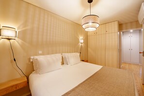 Una camera da letto con un letto, lampade sui comodini, un armadio e una cabina armadio.
