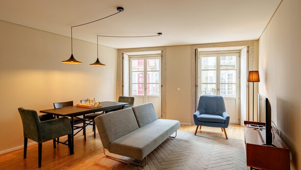 Un salon moderne comprenant un canapé, une table à manger, des chaises et un téléviseur.