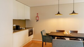Une cuisine moderne avec des meubles blancs, un plan de travail en bois et un coin repas comprenant une table et des chaises.