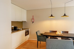 Een moderne keuken met witte kastjes, een houten aanrecht en een eethoek met een tafel en stoelen.