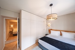 Un dormitorio con cama, armario, lámpara de mesita de noche e iluminación colgante.