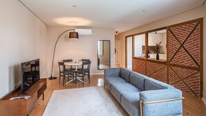A modern living room with a sofa, dining table, chairs, a TV, and a fireplace.