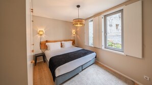 A bedroom with a bed, bedside lamps, a window, and a door.
